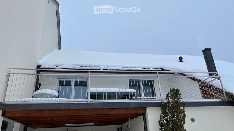 Balcony with metal railing, snow-covered roof, and snow-covered furniture.