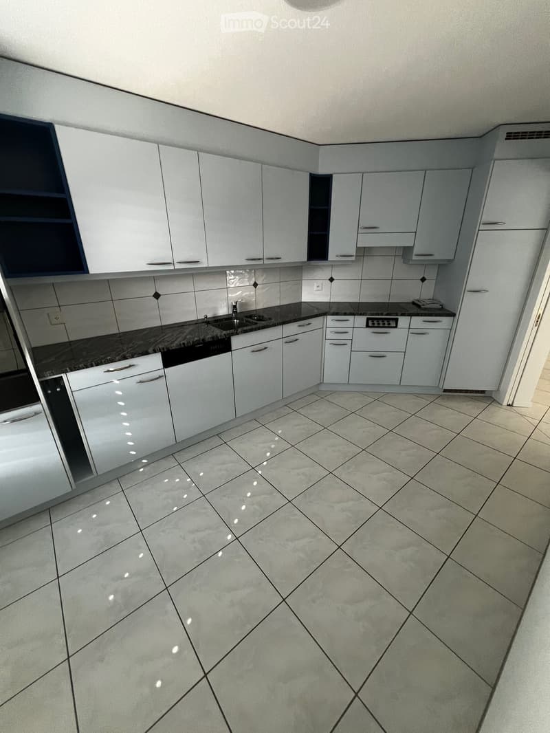 Modern kitchen with white cabinets, granite countertops, and tiled flooring. Features a sink, faucet, and dishwasher.