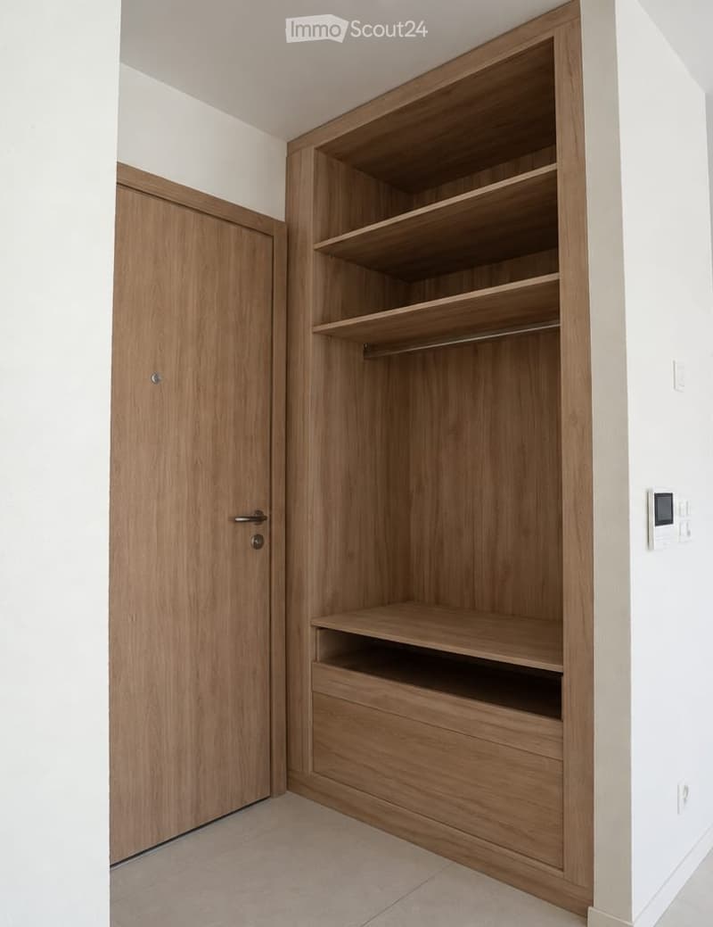 Empty closet with wooden shelves and a closed wooden door, featuring a clean and minimalist design.