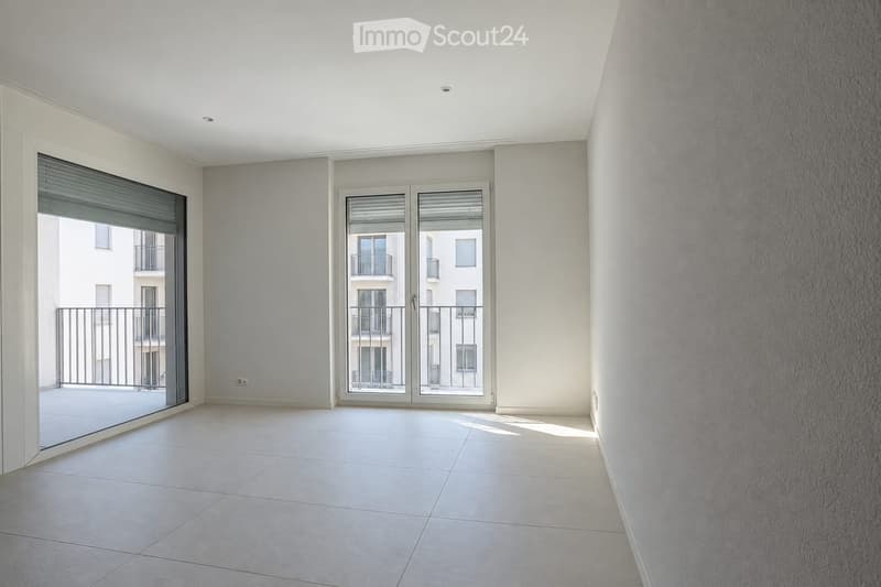 Empty room with white tiled flooring, white walls, and large sliding glass doors leading to a balcony.