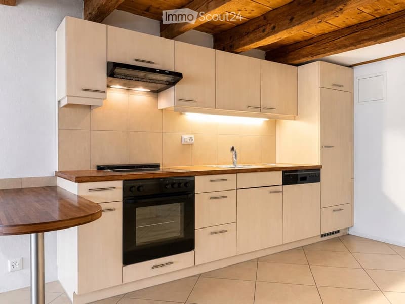 Modern kitchen with light-colored cabinets, stainless steel appliances, and a wooden countertop.