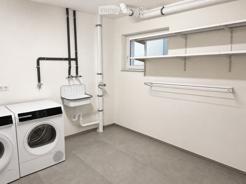Clean, modern bathroom with a washing machine, sink, shelves, and a rod for hanging items.