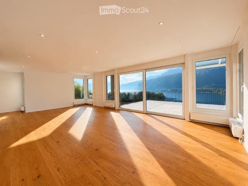Bright, empty room with wooden flooring, large windows, and panoramic mountain view. No furniture or equipment present.