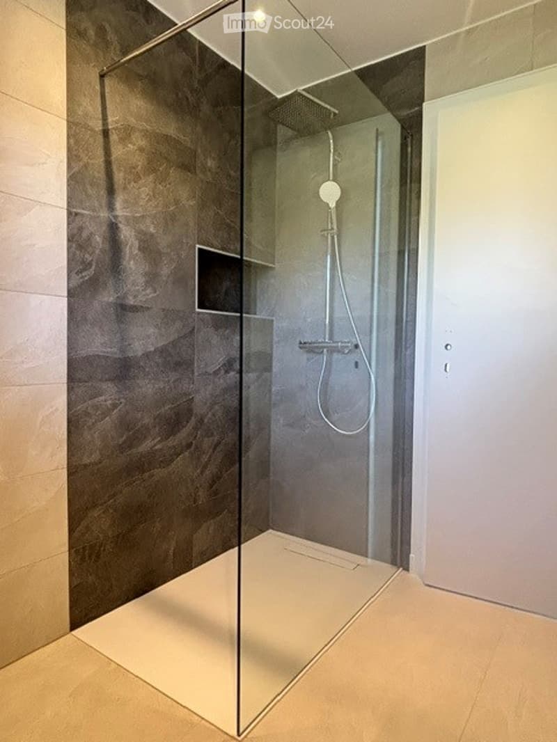 Modern bathroom with a glass-enclosed shower stall, sleek showerhead, and minimalist design.