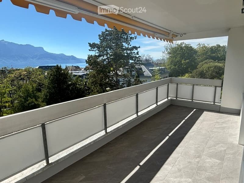 Balcony with tiled floor, white railing, and scenic mountain and lake view.