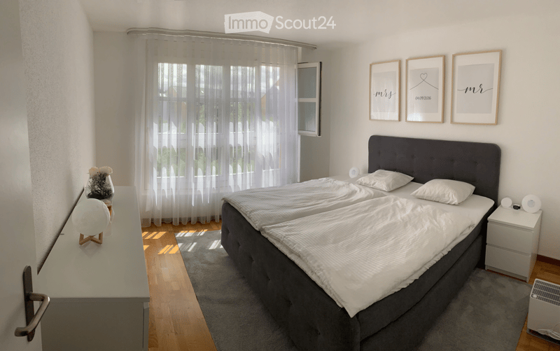 Bright bedroom with two single beds, nightstands, lamps, a vase with flowers, and framed artwork on the wall.