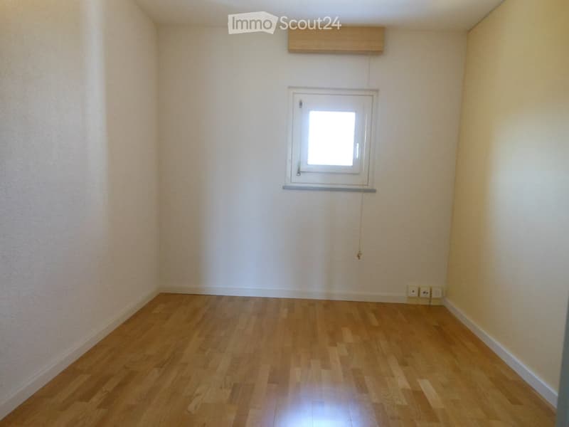 Empty room with light wooden flooring, white walls, and a single window with a simple wooden blind. No furniture or equipment present.