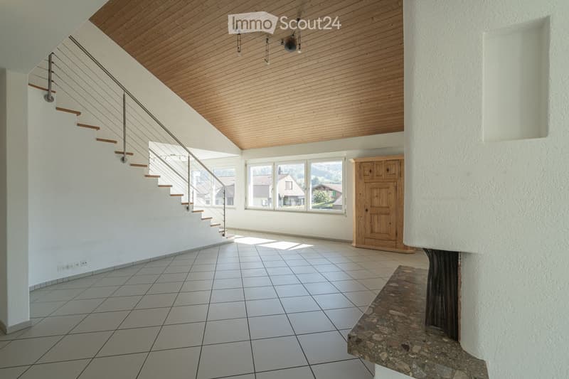 Bright hallway with a modern staircase featuring wooden steps and a metal railing, large windows, and a wooden cabinet.