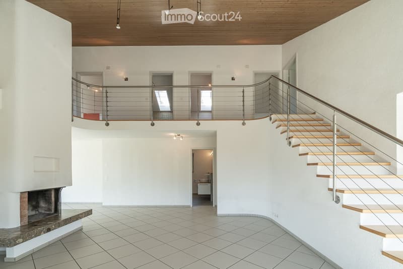 Modern hallway with a staircase leading to an upper level, featuring a metal railing, wooden steps, and a fireplace on the left side.