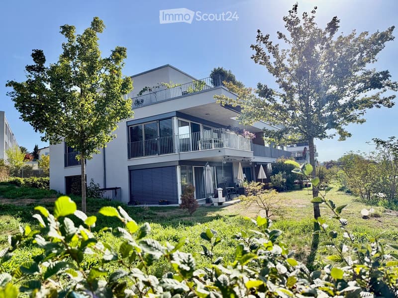 Modern two-story house with balconies, large windows, and a well-maintained garden area.