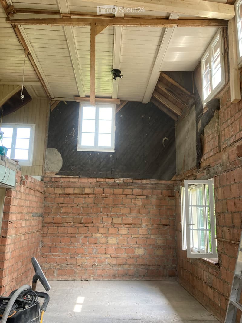 {"visible_features":[],"type":"Room","description":"This image shows the interior of a room with a wooden ceiling and exposed brick walls. The room appears to be in a state of renovation or construction, with some debris and construction materials visible