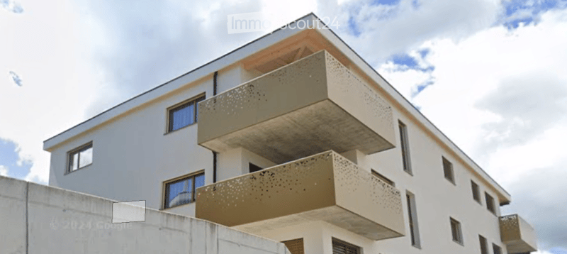 Modern multi-story building with white facade and balconies featuring decorative metal railings.