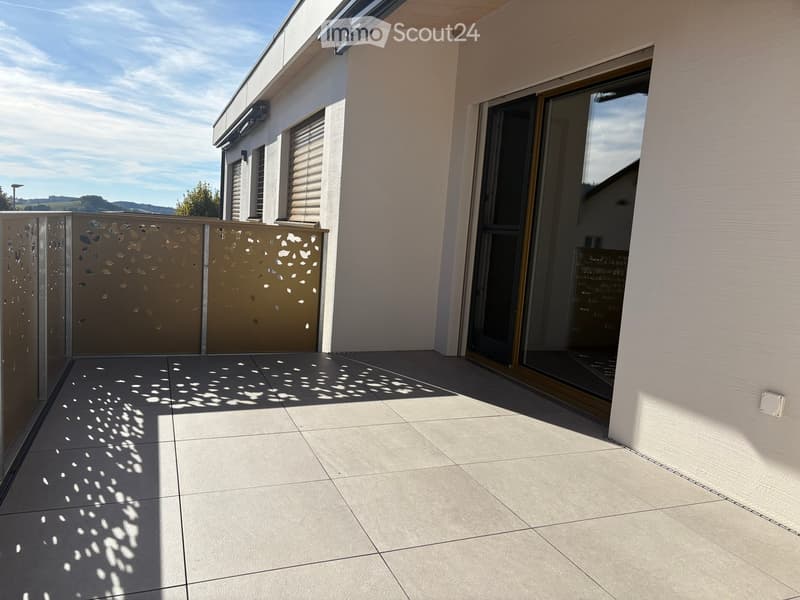 Balcony with tiled floor, sliding glass door, decorative metal screen, and view of the surrounding landscape.