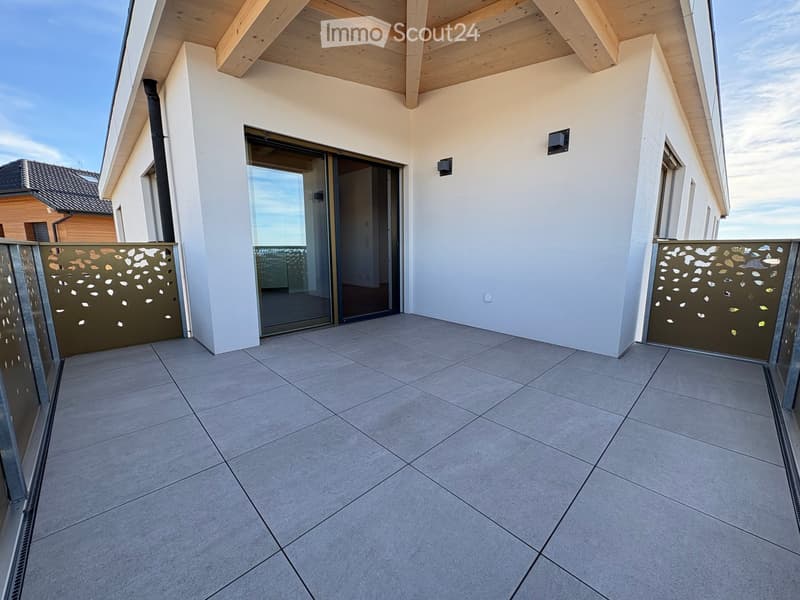 Modern balcony with tiled floor, glass sliding doors, decorative metal screens, and white walls.