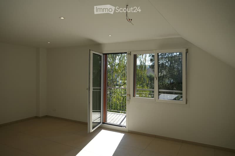 Empty room with tiled floor, white walls, and large windows with a sliding glass door leading to a balcony.