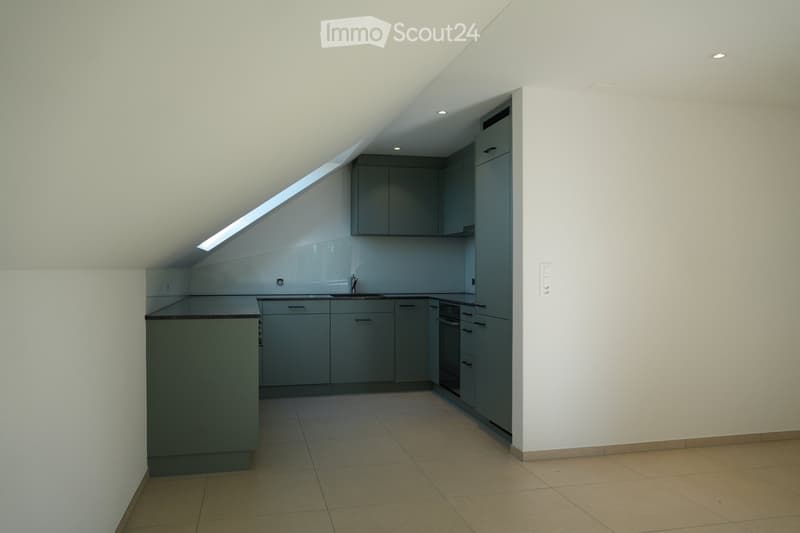 Modern kitchen with grey cabinets, a sink, and an oven, featuring a skylight window and tiled flooring.