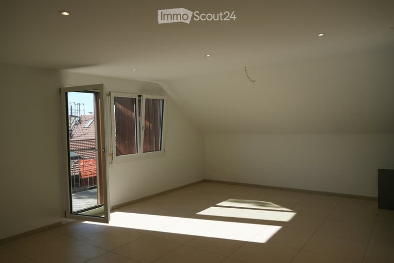 Empty room with tiled floor, white walls, and a large window with wooden shutters. Natural light streams in, casting shadows on the floor.