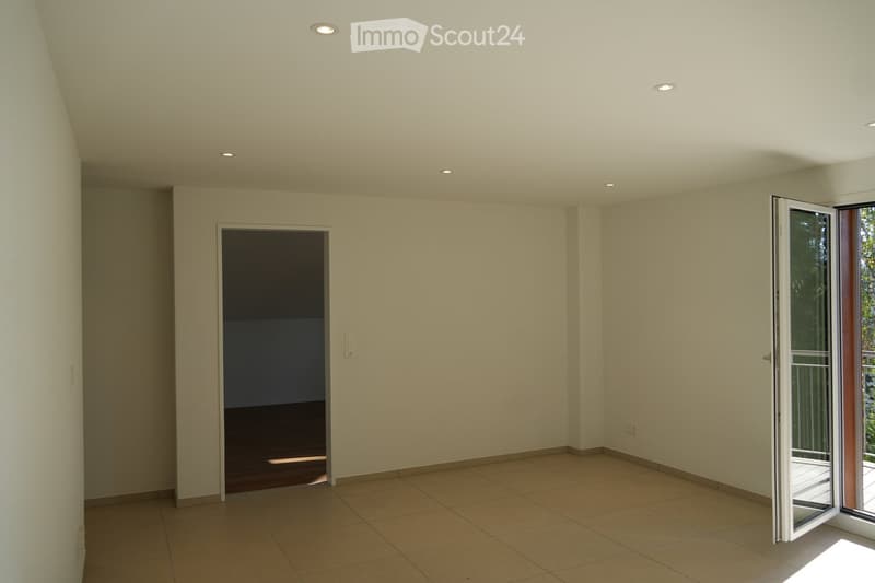 Empty room with beige tiled flooring, white walls, and recessed ceiling lighting. Features an open sliding door leading to a balcony and a closed door to another room.