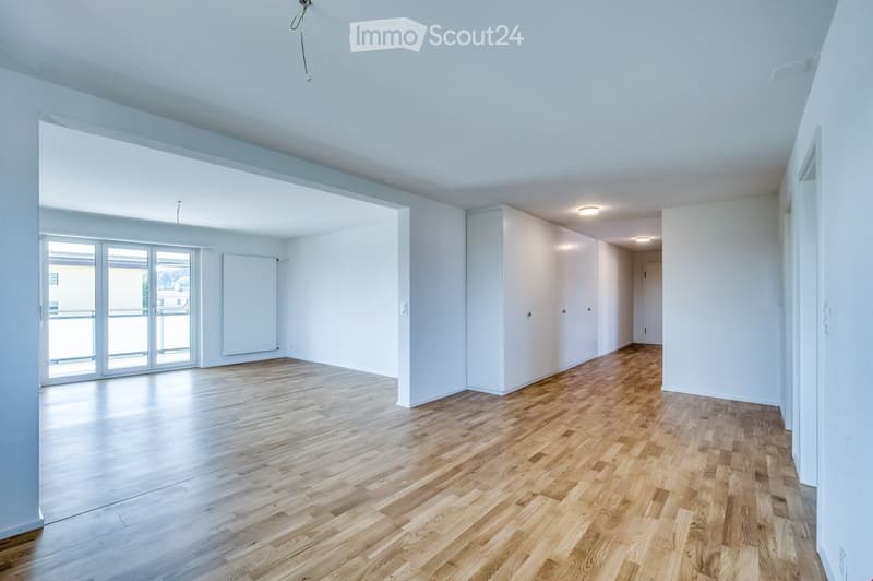 Empty room with wooden flooring, white walls, large windows, and built-in white cabinetry.
