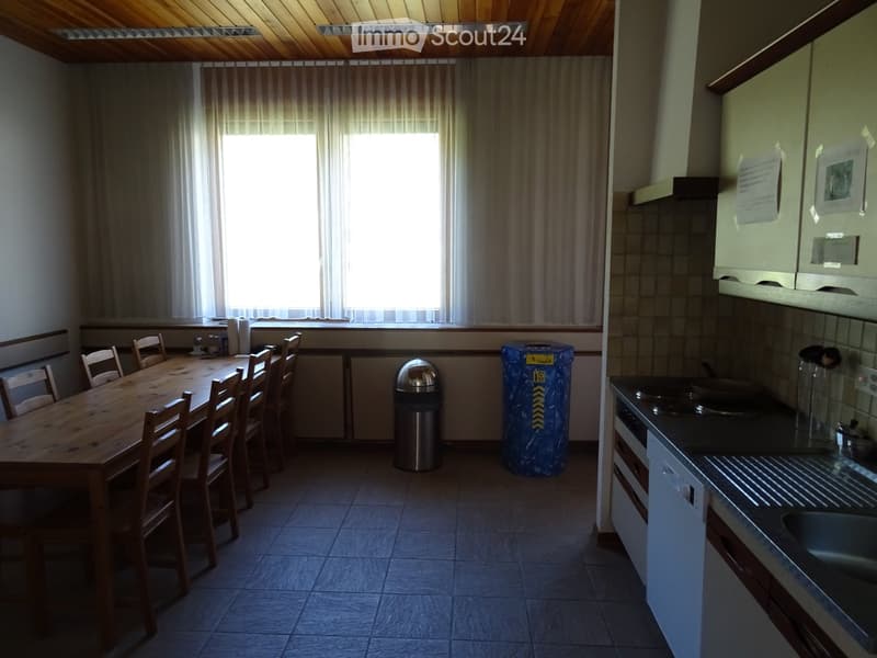 A combined kitchen and dining area with a wooden dining table, chairs, a stove, sink, and cabinets.