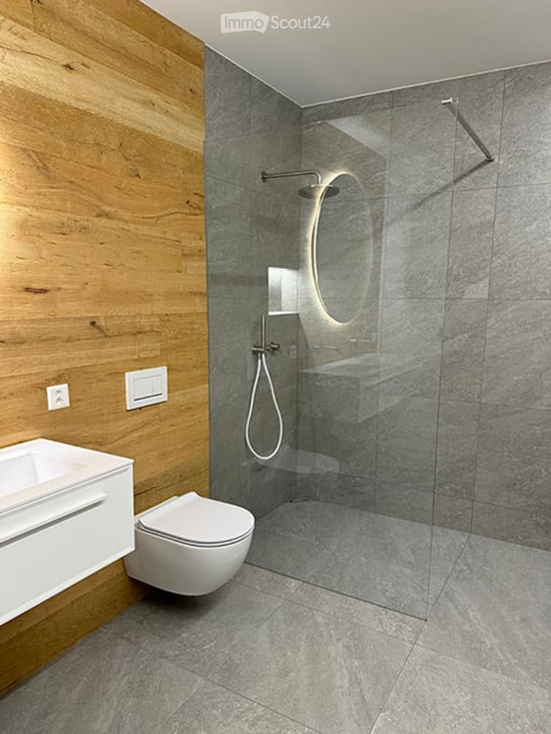 Modern bathroom with wooden wall paneling, a glass-enclosed shower, a floating sink, and a toilet.