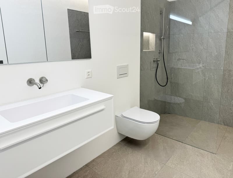 Modern bathroom with a white bathtub, toilet, glass-enclosed shower, and sleek fixtures.