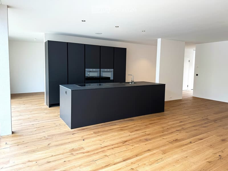 Modern kitchen with dark grey cabinets, a central island, and a wooden floor.