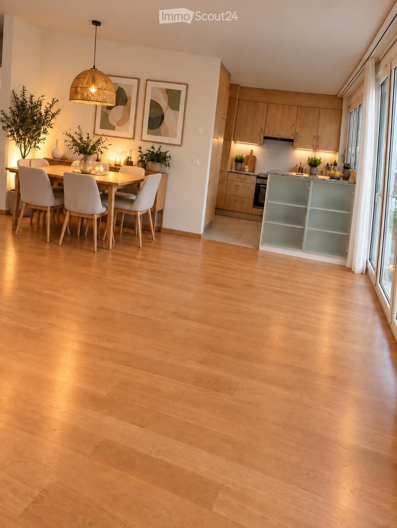 Open-plan dining and kitchen area with light wooden flooring, modern light wood cabinets, a dining table with four chairs, pendant lighting, and decorative vases.