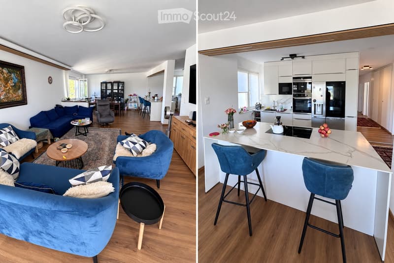 The image shows a modern, open-concept living and dining area with a kitchen. The living area features a blue sectional sofa, a coffee table, and several chairs. The dining area includes a round table with chairs. The kitchen has white cabinets, stainless