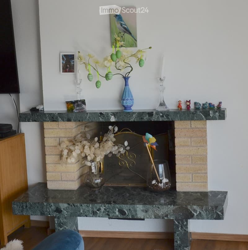 Fireplace with marble mantel, decorative vases, candles, and picture frames on the mantel.