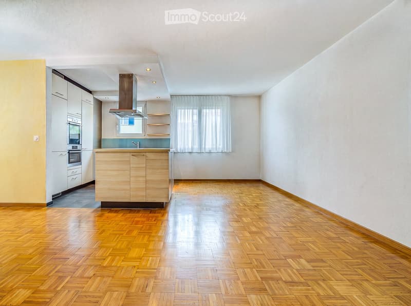 Empty kitchen with wooden herringbone flooring, white walls, and built-in cabinets. No appliances or furniture are present.