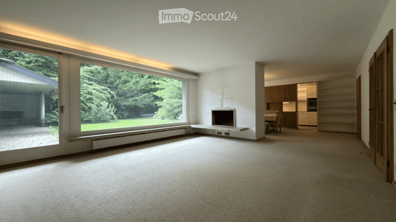 Bright living room with large windows, fireplace, dining area visible through an open doorway.