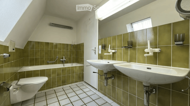 Modern bathroom with green tiled walls, white fixtures, and a skylight window providing natural light.