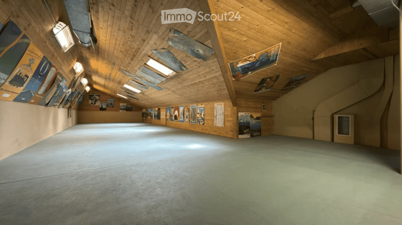 An empty room with wooden walls and ceiling, posters on the walls, and a concrete floor.