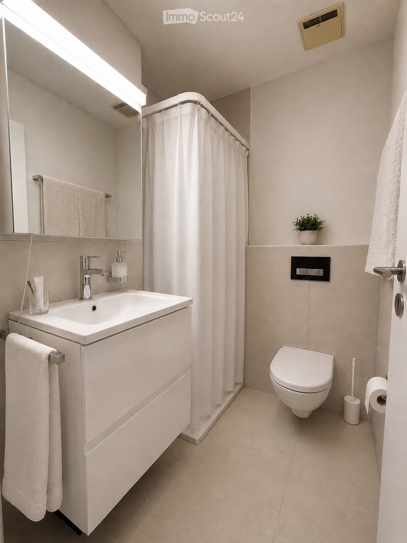 Modern bathroom with a white sink, mirror, toilet, and shower area with a curtain. Includes towels, a small plant, and a toothbrush holder.
