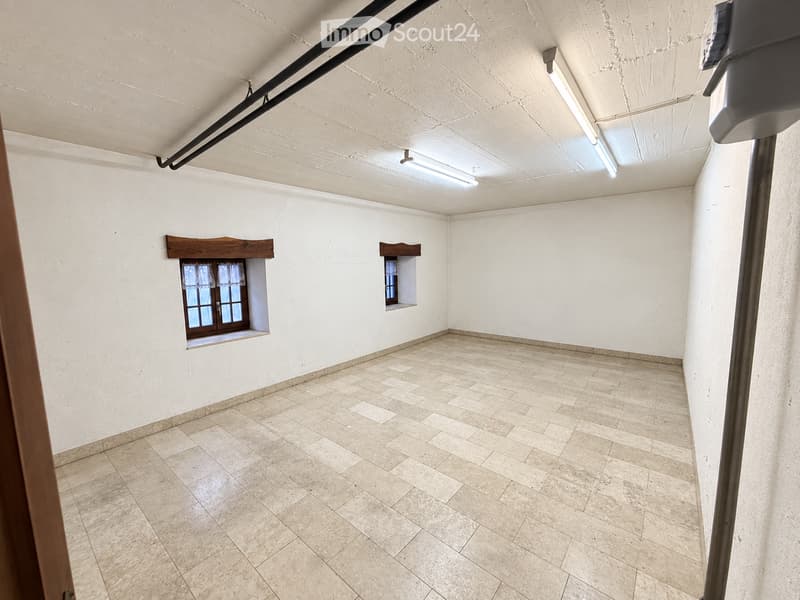 Empty room with white walls, tiled floor, and two small windows with wooden frames.
