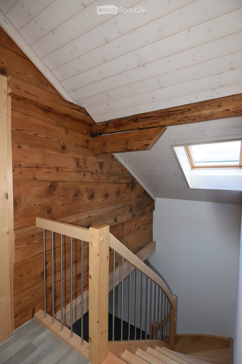 Wooden staircase with a modern metal railing, wooden walls, and a skylight window at the top.