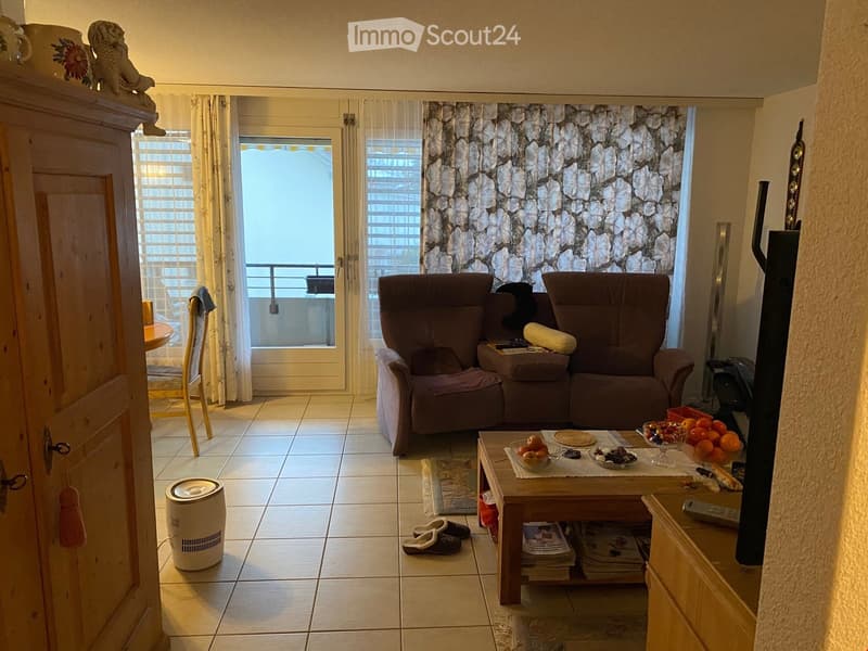 Living room with a sofa, coffee table, fruit bowl, and a balcony view.