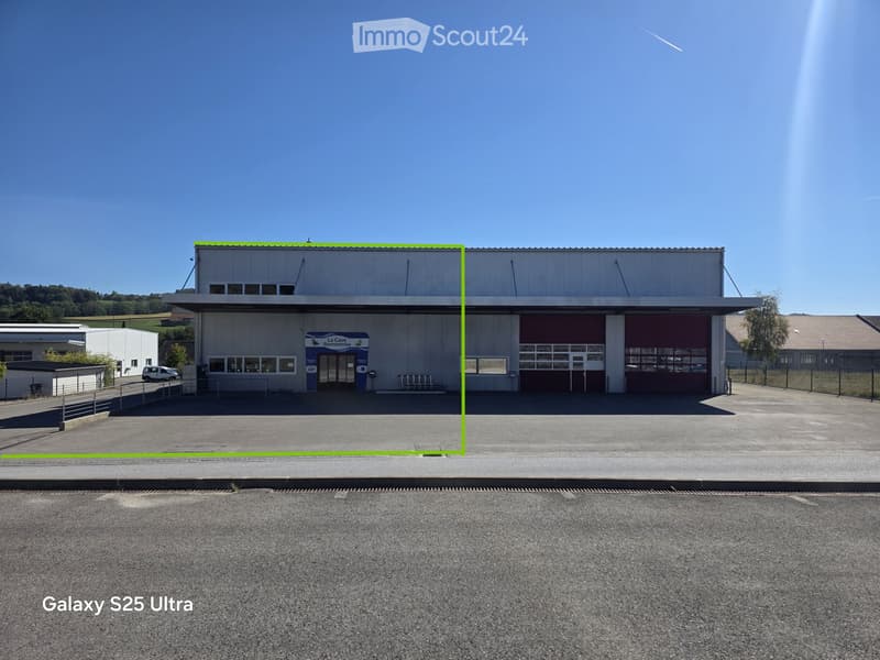A large industrial-style building with a flat roof, large garage doors, and a sign reading "La Cave Romontoise".