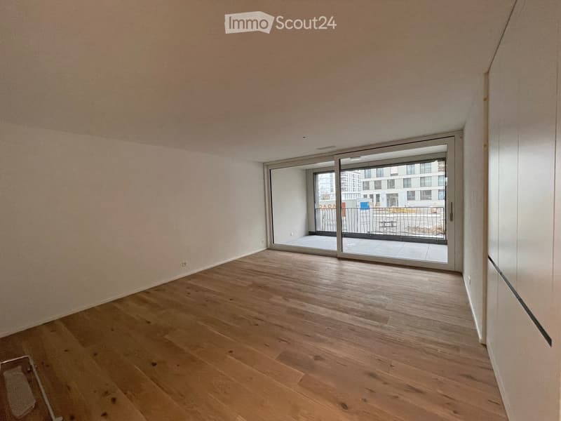 Empty room with wooden flooring and large sliding glass doors leading to a balcony area.