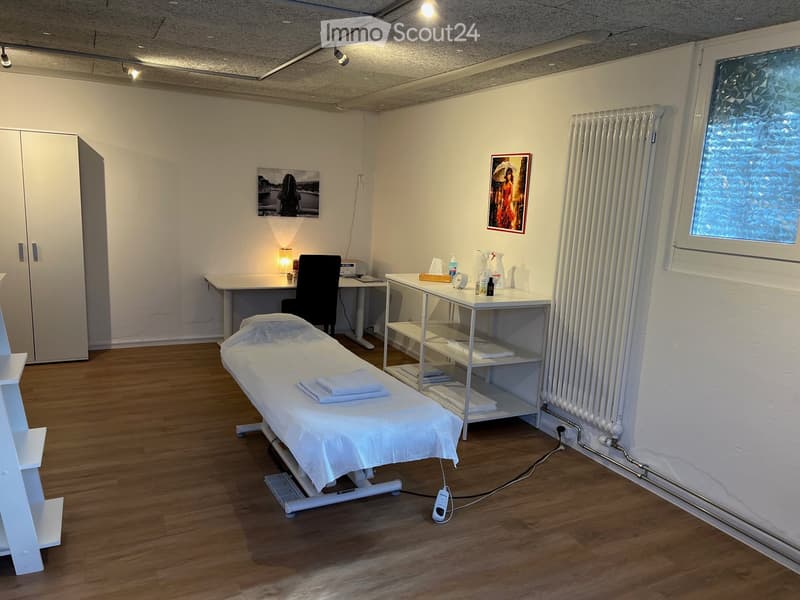 massage table, white shelves, white cabinets, white radiator, desk, chair, picture frames, lamp