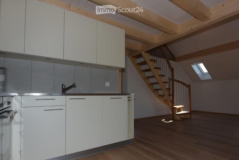 Modern kitchen with white cabinets, stainless steel appliances, and a wooden staircase leading to an attic space.