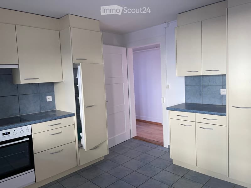 Modern kitchen with light-colored cabinets, a dark countertop, and an oven. The space is clean and organized with tiled flooring.