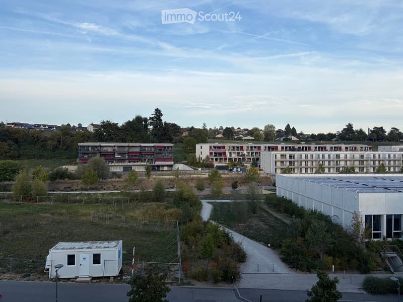A modern residential complex with multiple apartment buildings, surrounded by greenery and pathways.