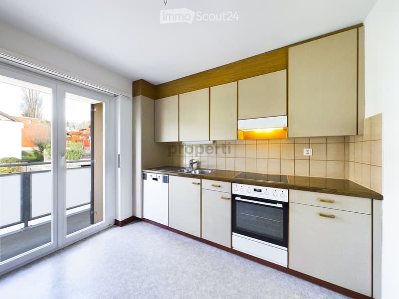 Modern kitchen with white cabinets, stainless steel appliances, and a wooden countertop. Features a sink, faucet, oven, dishwasher, and range hood.