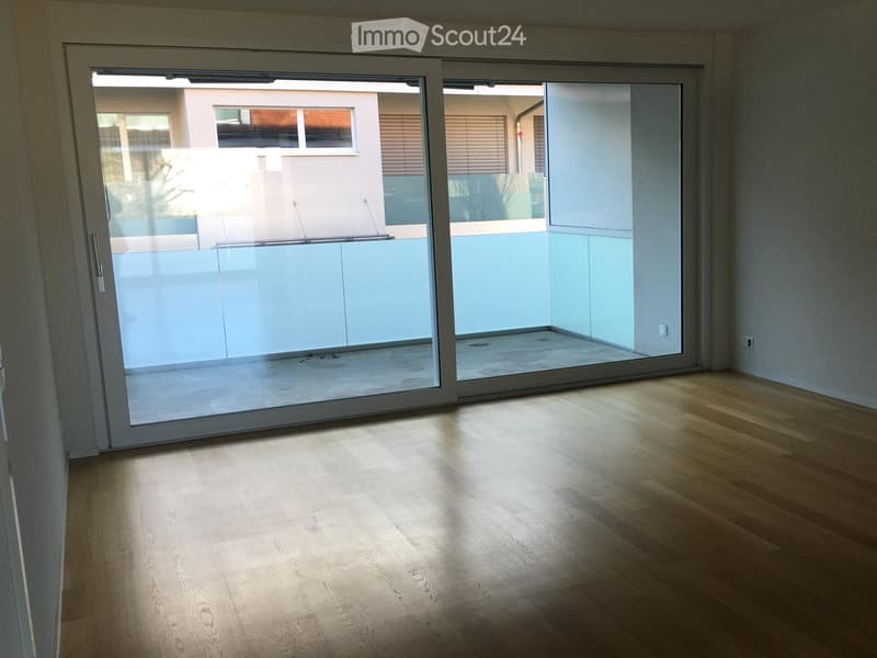empty room with wooden floor, large sliding glass doors leading to balcony