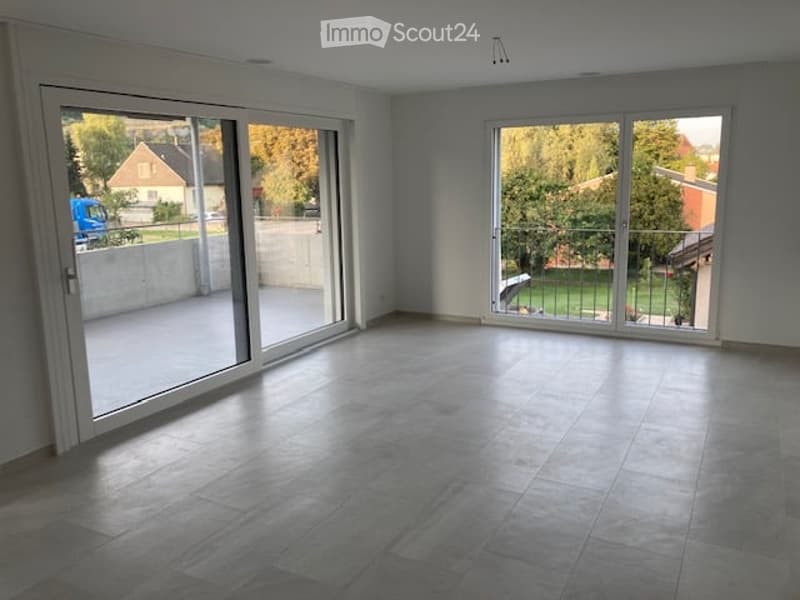 Empty room with large sliding glass doors leading to a balcony, tiled floor, and white walls.