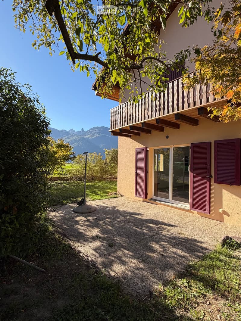 Two-story house with a balcony, purple shutters, and a scenic mountain view in the background.