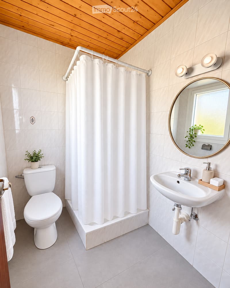 Modern bathroom with white tiles, a toilet, a sink with a modern faucet, a round mirror, a shower curtain, and a small plant on the windowsill.