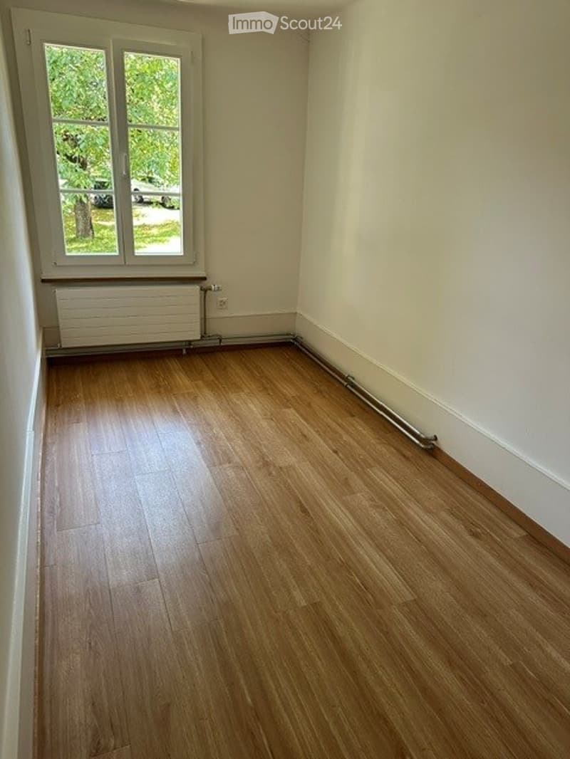 Empty room with wooden flooring, white walls, and a window with a radiator below it. No furniture or equipment present.